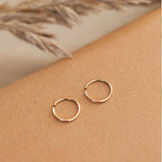 A pair of tiny gold hoops in three different sizes. Each pair sold separately.