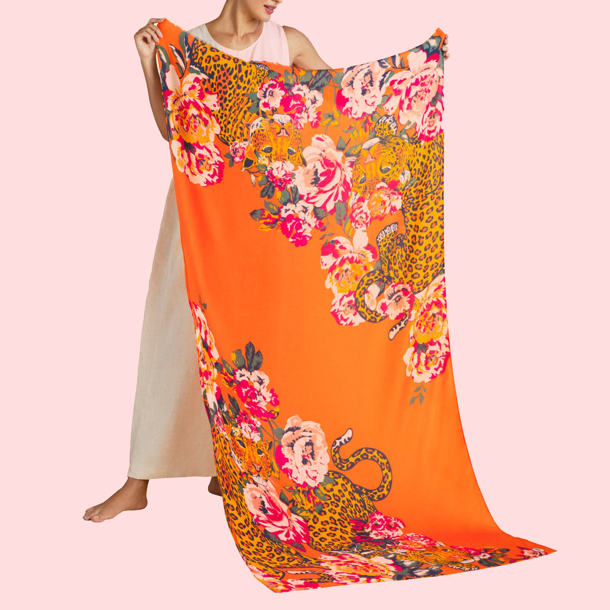 On a pink background is an orange scarf with a leopard and floral design. 