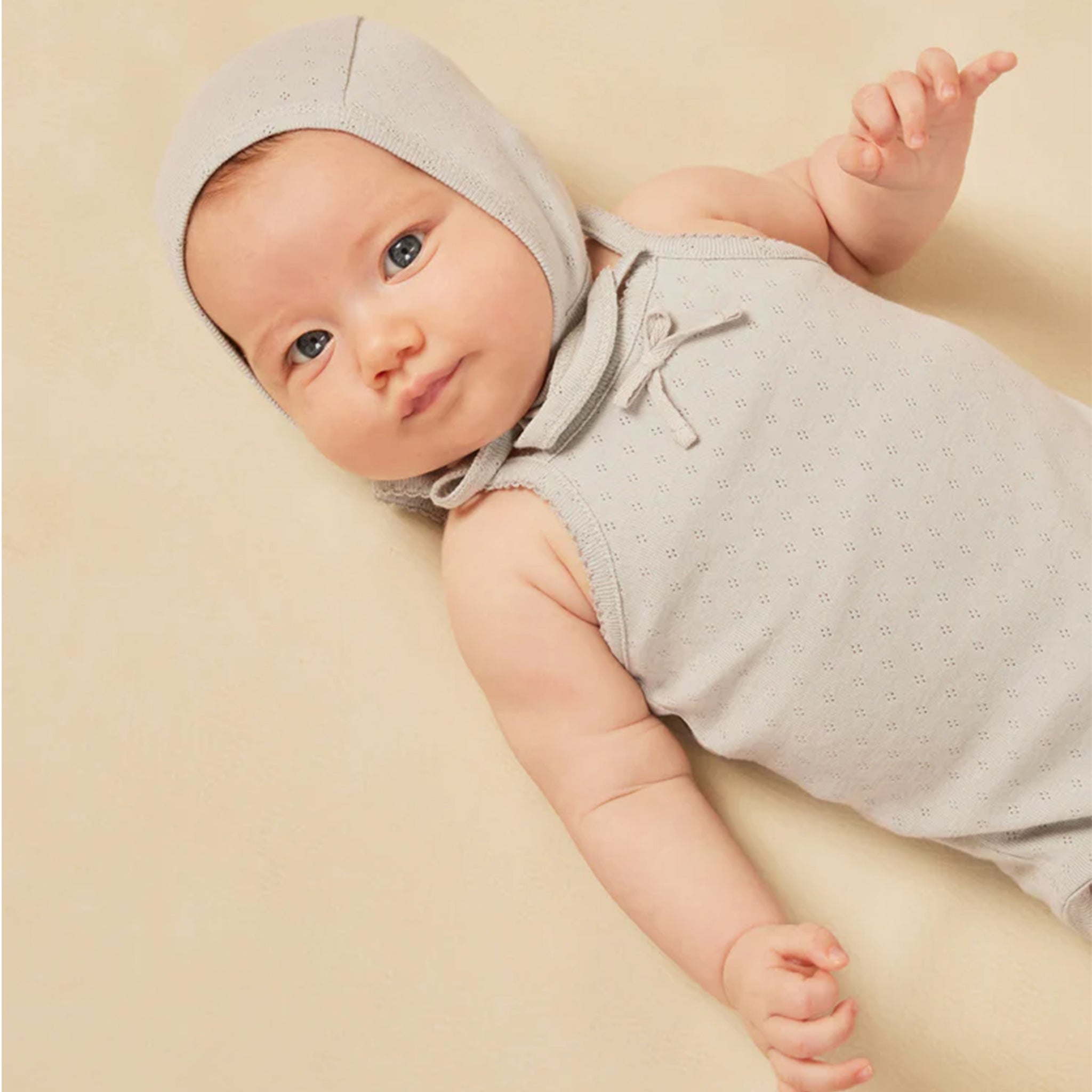 On a tan background is a light blue tank onesie with snap closure and a small bow detail at the top.