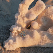 A gold chain necklace with a round pendant with a starfish on it.