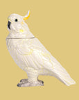 A white and yellow cockatoo shaped jar with a removable lid.