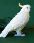 A white and yellow cockatoo shaped jar with a removable lid.