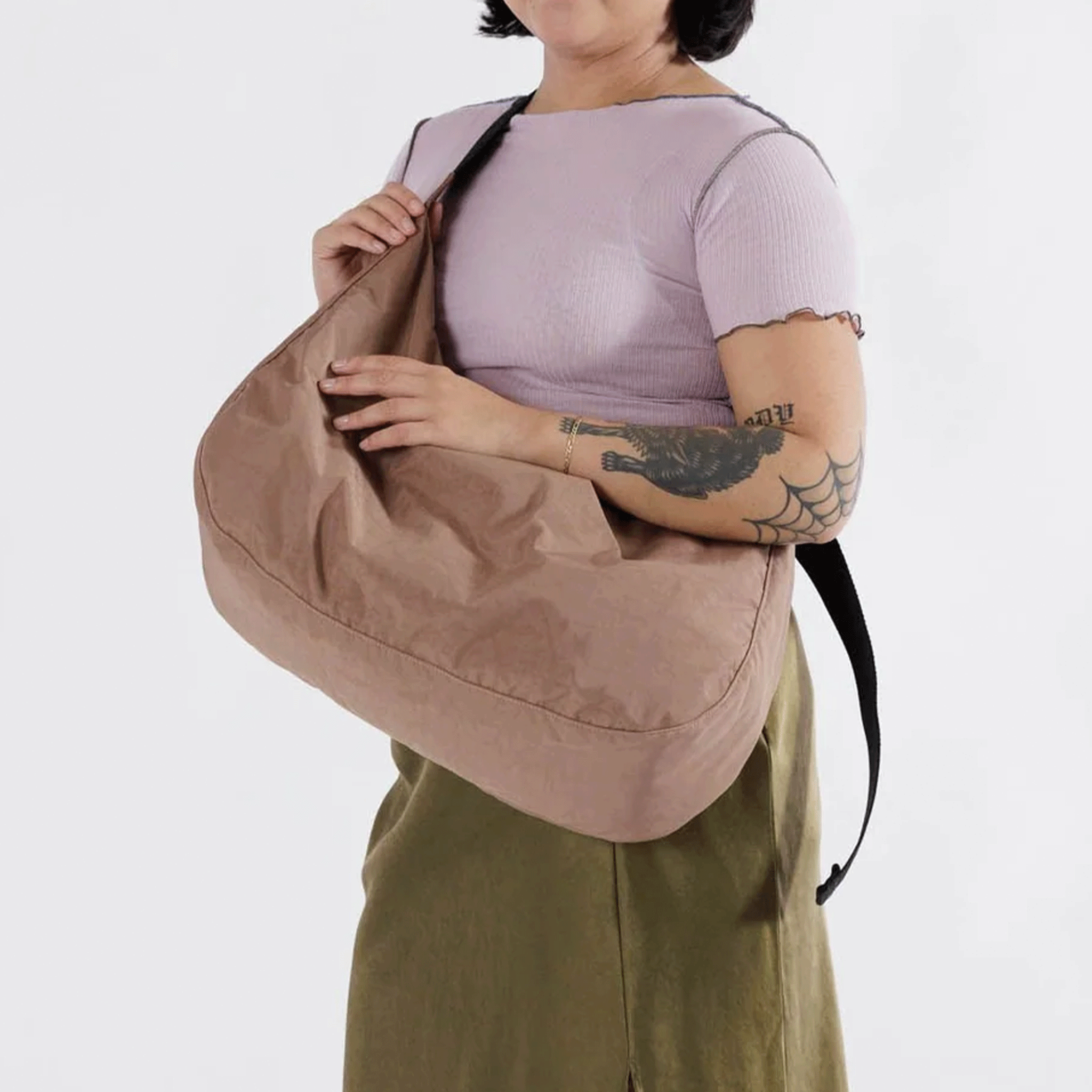 On a white background is a model holding the cocoa brown large crescent bag. 