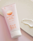 On a pink and white background is a light pink bottle of lotion with orange text on the front that reads, "Mersea Sun Coconut Sugar Sea Whip Body Cream".