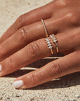 A model wearing the Cooper Ring which is a thin gold band with 5 cz diamonds stacked next to one another across the top.