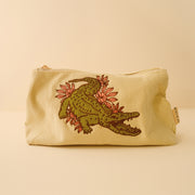 A pale corduroy pouch with a crocodile embroidered design on the front.