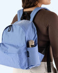 A blue nylon backpack with a side pocket and front zip pockets and black details.