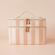 An apircot and light pink striped vanity case / cosmetic bag with two layers of compartments and a handle at the top for easy carrying.