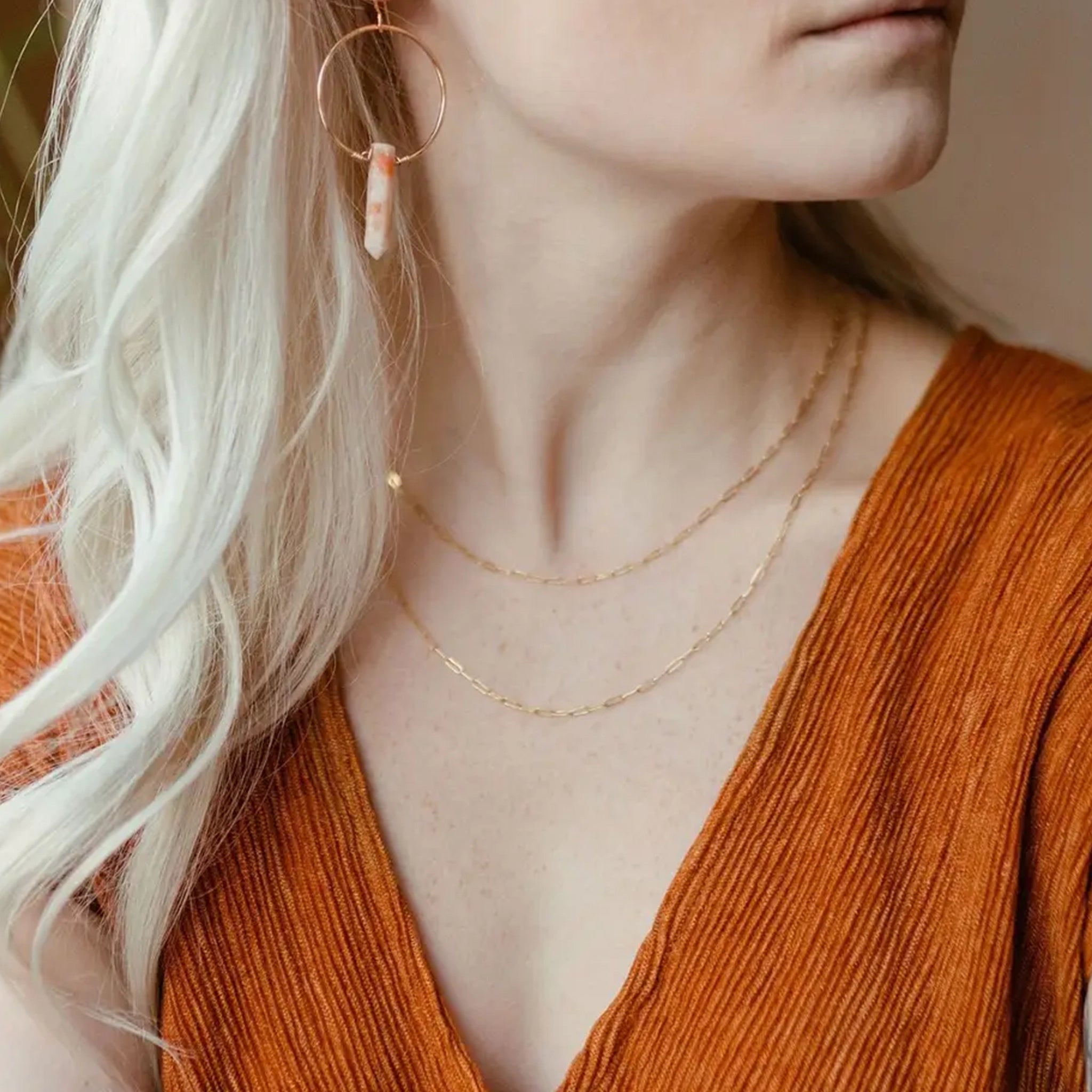 A dainty gold link chain necklace worn on a model layered with other pieces. 