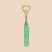 A brass bottle opener with a light green resin handle.
