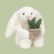 A cream colored bunny stuffed animal holding stuffed toy plant.