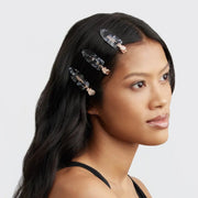 On a white background is a model wearing the creaseless clips with a black terrazzo print.