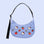 On a blue background is a blue crescent bag with embroidered Hello Kitty shapes and icons on it. 
