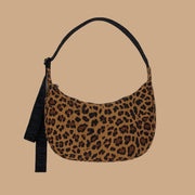 A medium sized crescent shaped bag with a leopard print and black adjustable strap.