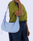 A light blue nylon handbag with an arched crescent shape and adjustable strap.