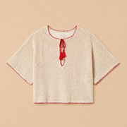 Beige knitted top with red trim on a beige background