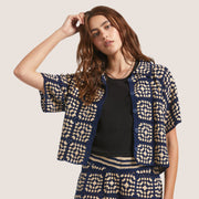 A crochet dark blue and cream colored button up short sleeve top.