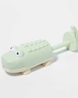 A crocodile shaped beach, pool or bath toy in a green and cream shade.