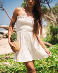 A cream smocked mini strapless dress.