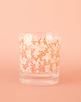 A clear short drinking glass with a pink and white daisy print.