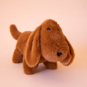 A brown dachshund shaped stuffed animal toy.