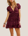 A maroon mini dress with ruffle details and a v-neck with puff sleeves.