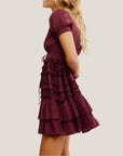 A maroon mini dress with ruffle details and a v-neck with puff sleeves.