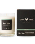 A glass candle with white wax and a black label that reads, 'Del Mar Sea Spray & Coconut Water'.
