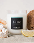 A glass candle with white wax and a black label that reads, 'Del Mar Sea Spray & Coconut Water'.