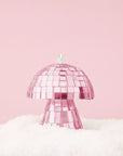 On a pink snowy background is a pink disco mushroom ornament.
