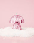 On a pink snowy background is a pink disco mushroom ornament.