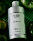 A silver bottle of dish soap with a light blue label that reads, 'Flamingo Estate Dish Soap'.