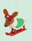 A brown dachshund shaped ornament on skis and wearing a green jacket.