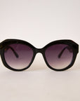 A black pair of rounded sunglasses with a purple black lens.
