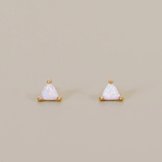 On a tan background is a triangle shaped stud earring with gold plating and a white opal stone center.