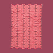 A pink and red piping edge bath towel with a wavy end on both sides.