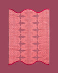 A pink and red piping edge hand towel with a wavy end on both sides.
