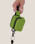 A green nylon bag charm in the shape of a mini fanny pack.