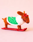 A brown dachshund shaped ornament on skis and wearing a green jacket.