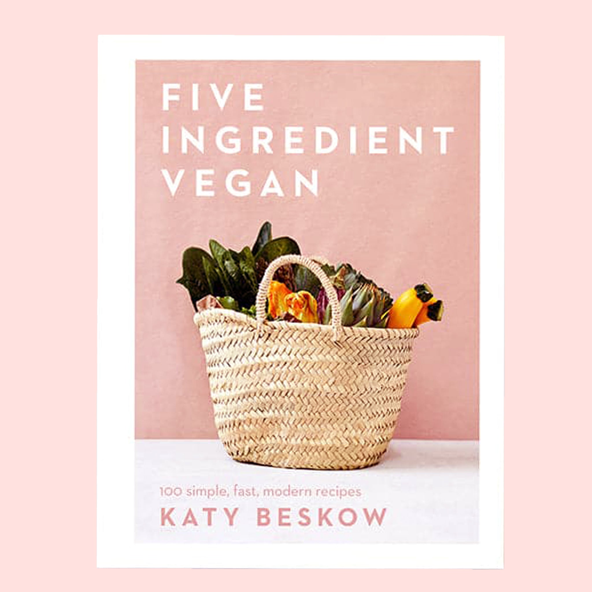 A salmon pink book cover with a neutral basket full of veggies along with a white border and white text that reads, "Five Ingredient Vegan'.