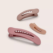 On a neutral background is three different hair clips in shades of dusty rose and terracotta.