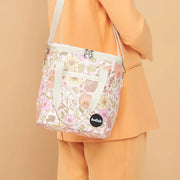 A pink and yellow muted floral printed cooler bag with a strap.