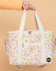 An ivory, floral print picnic bag with white straps and zippers.