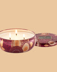 A red and tan floral print metal tin with a three wick candle inside.