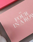 A pink box filled with a four in a row board game and white text that reads, "No 8 Four In A Row".