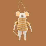 A white mouse shaped felt ornament wearing a yellow striped sweater on a nutmeg colored background.