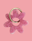 A fuchsia colored flower resin keychain with a silver loop for hanging.