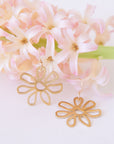 Gold hook earrings with a gold outline flower design.