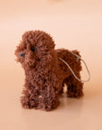 On a tan background is a brown furry poodle ornament.