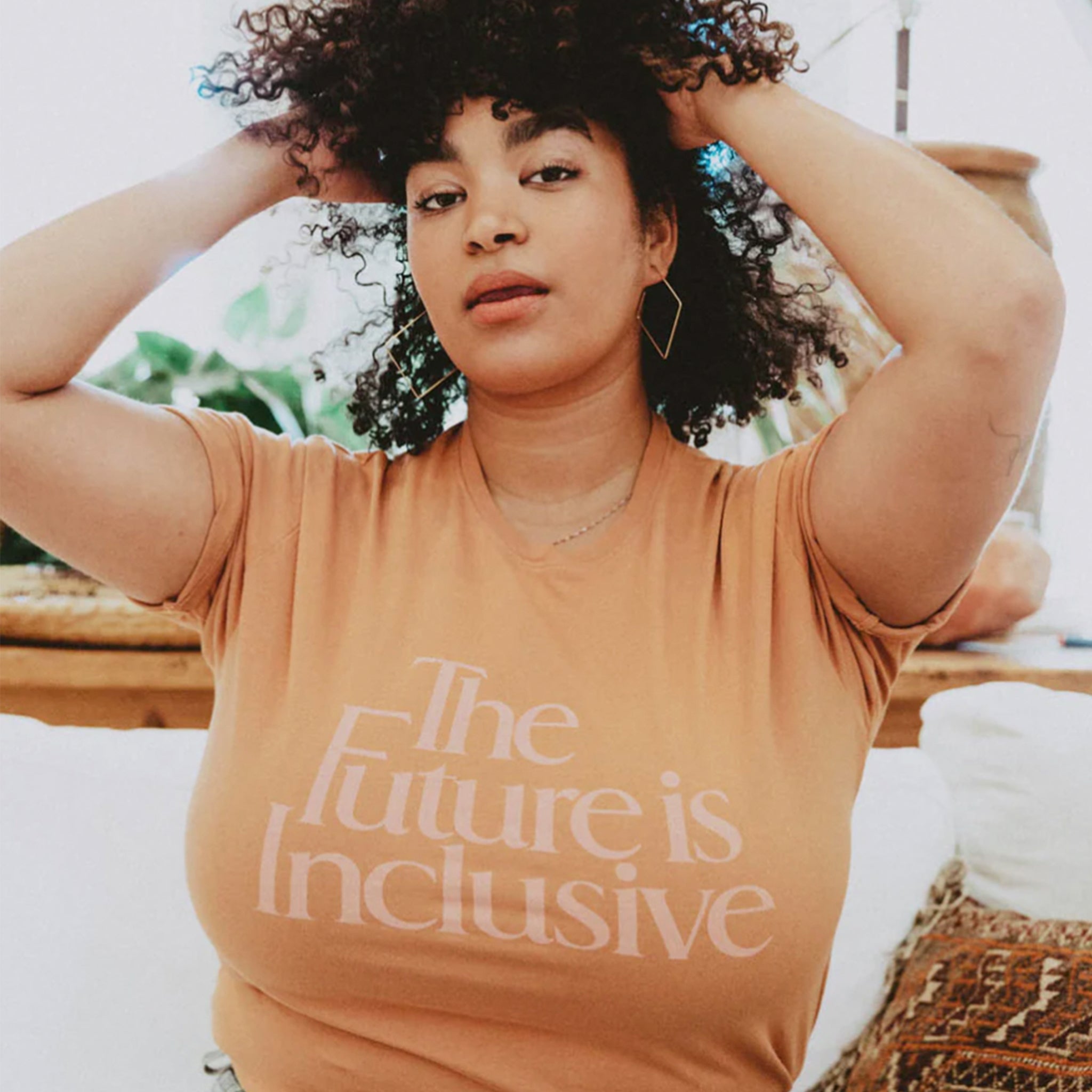 A peach t-shirt with text on the front that reads, "The Future is Inclusive.".